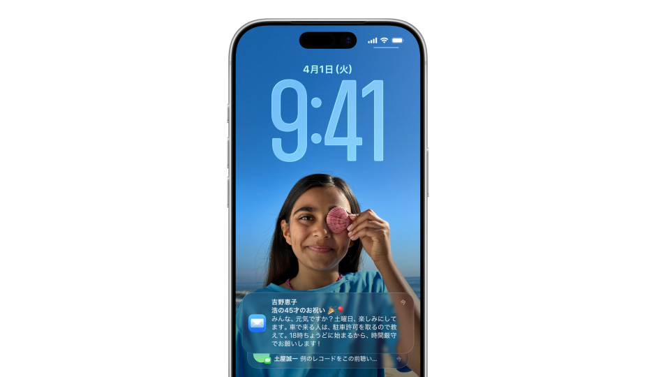 iPhoneのロック画面に写真と、Liquid Glassでできた時刻を表す数字が表示されており、下部に2件の通知が現れる