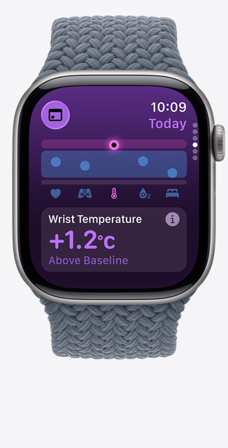 Apple Watch Series 11 z tytanową kopertą w kolorze łupku i plecioną opaską Solo w kolorze marynarskiego granatu. Na ekranie apka Parametry życiowe pokazuje wykres przedstawiający stan zdrowia i powiadomienie o temperaturze nadgarstka powyżej wartości bazowej. Na prawym boku urządzenia pokrętło Digital Crown.