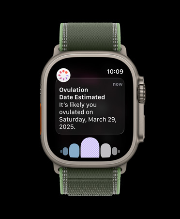 Apple Watch Ultra 3 med urkasse i farven naturligt titanium, notifikation om estimeret dato for ægløsning fra Min cyklus i appen Sundhed og Trail Loop-rem i blå/klar blå